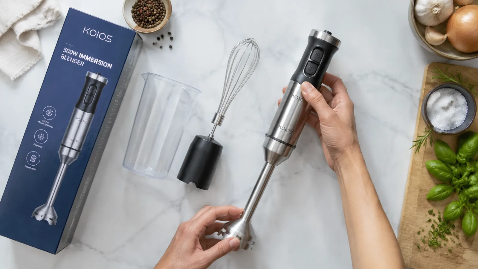 Overhead flat lay showing an immersion blender and its accessories laid out on a white kitchen counter