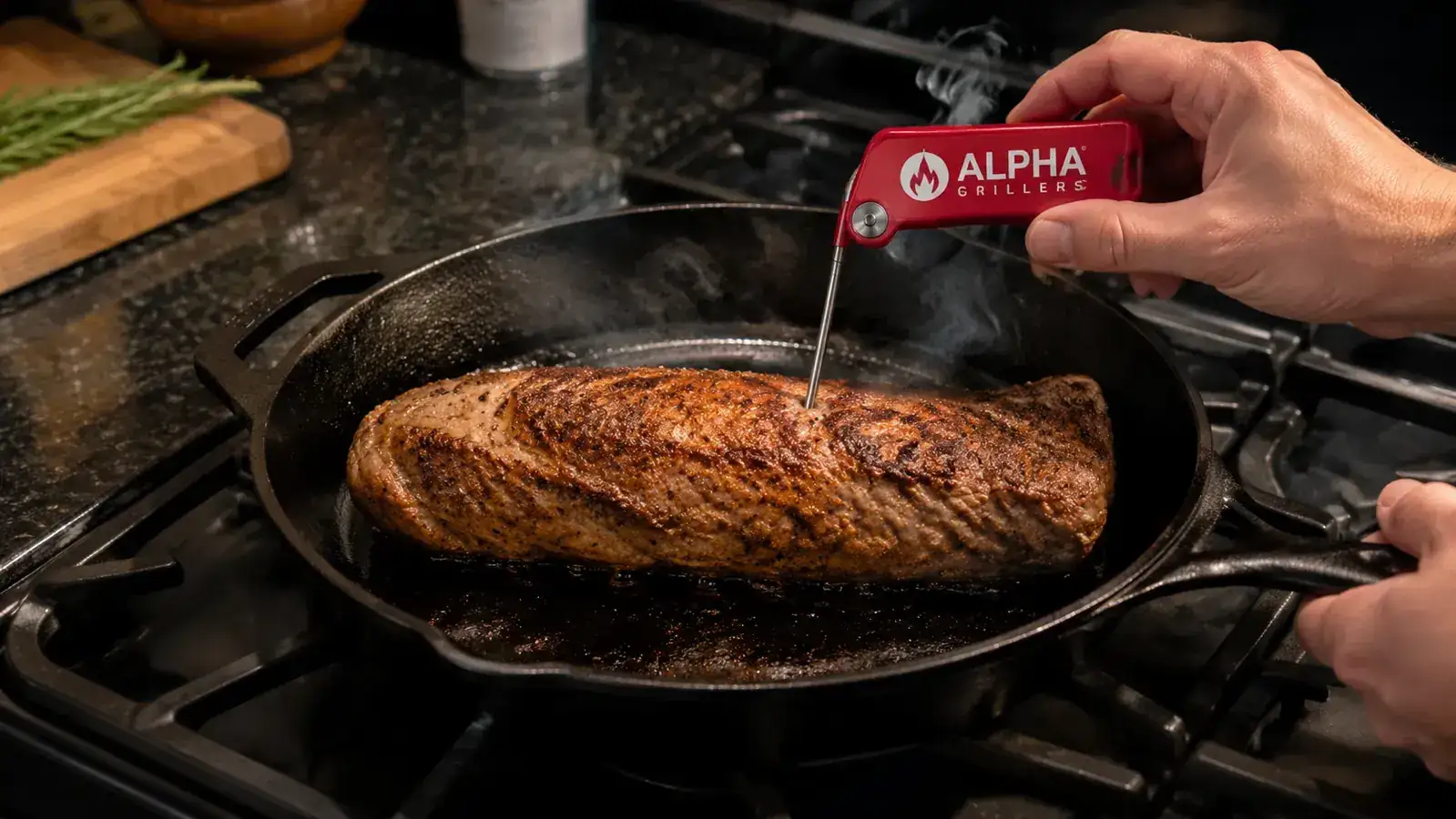 Hand inserting the Alpha Grillers thermometer probe into a pork tenderloin in a cast iron skillet on a stovetop