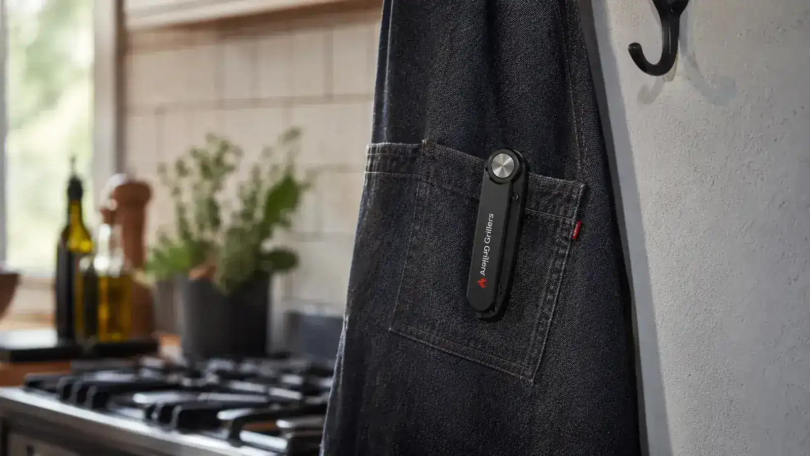 Alpha Grillers thermometer folded and clipped to the edge of an apron pocket