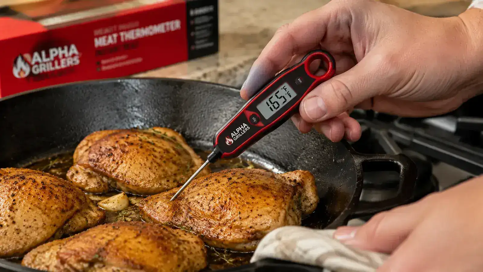 Hand inserting the Alpha Grillers instant-read thermometer probe into a chicken thigh in a cast iron skillet