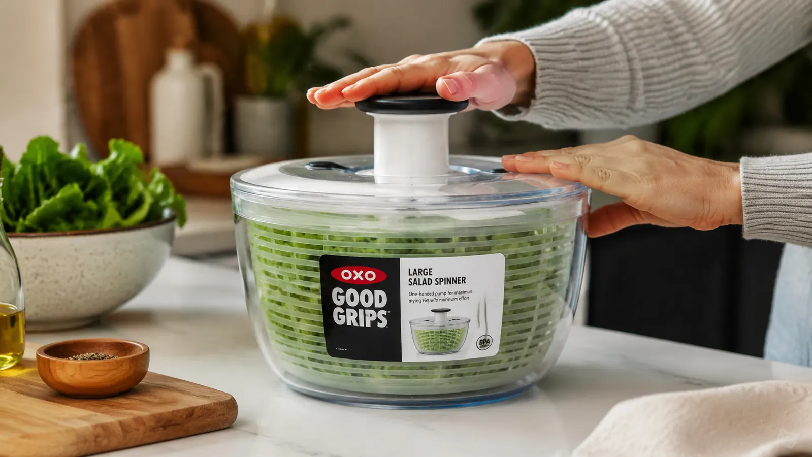 OXO Good Grips Salad Spinner sitting on a kitchen counter with freshly washed greens visible inside the clear bowl