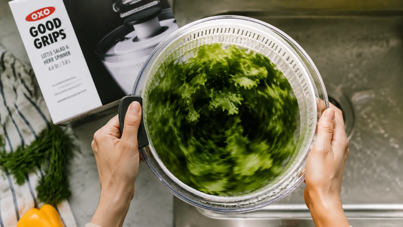 Salad spinner basket filled with wet lettuce leaves mid-spin, water droplets visible