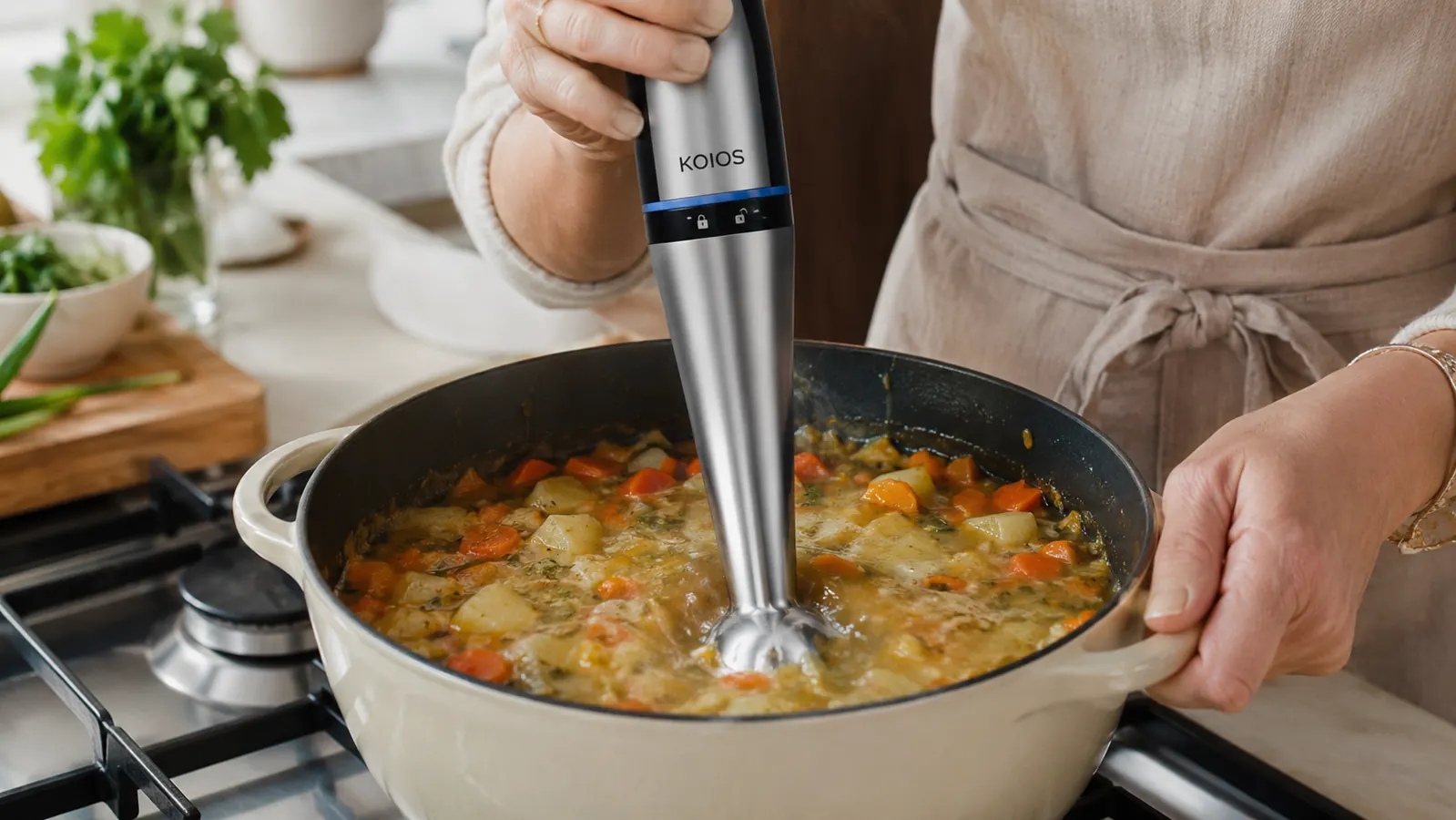 Hand holding the KOIOS immersion blender submerged in a pot of vegetable soup, blending directly in the pot