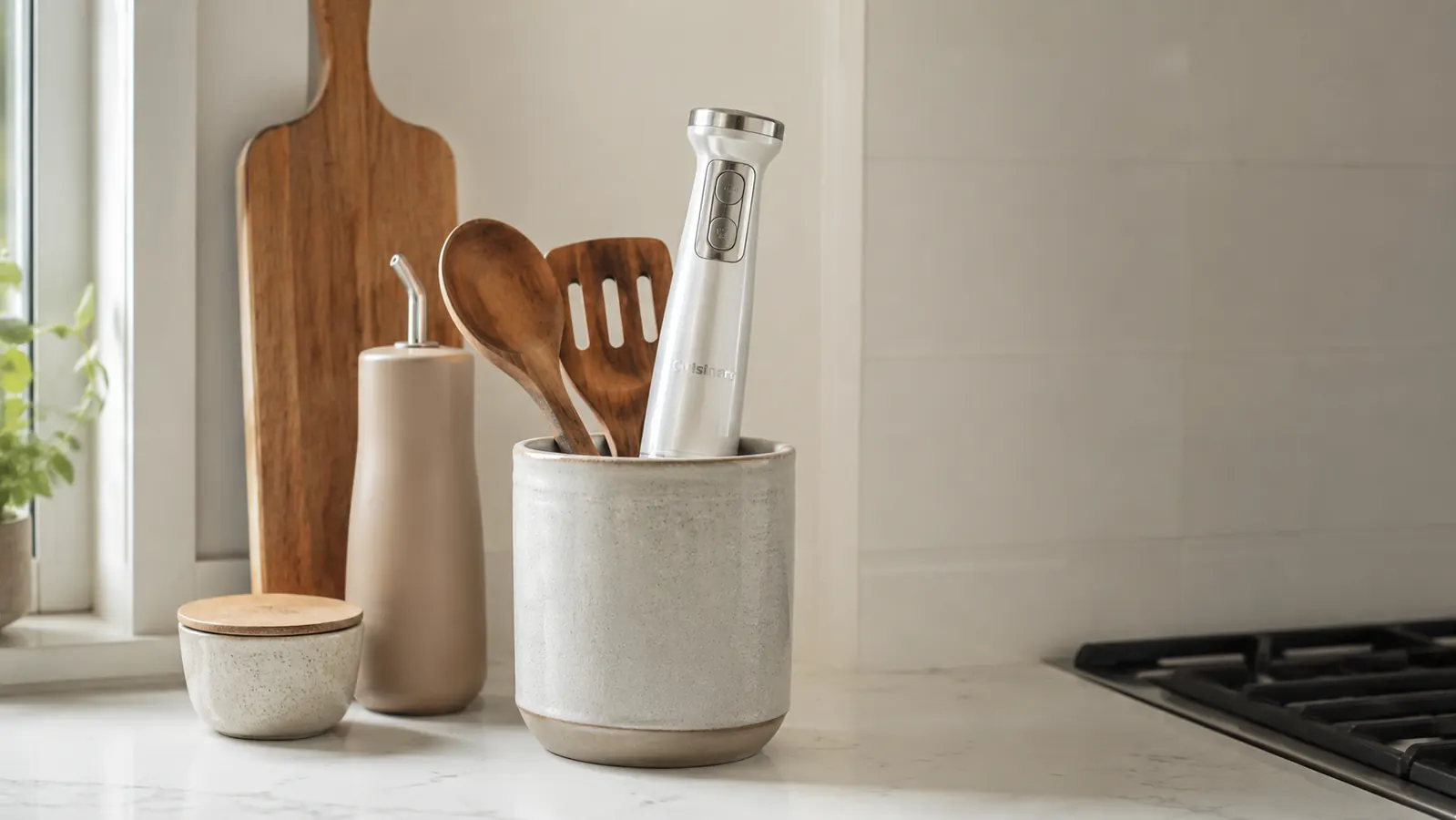 KOIOS immersion blender stored upright in a utensil crock beside a cutting board in a tidy kitchen drawer